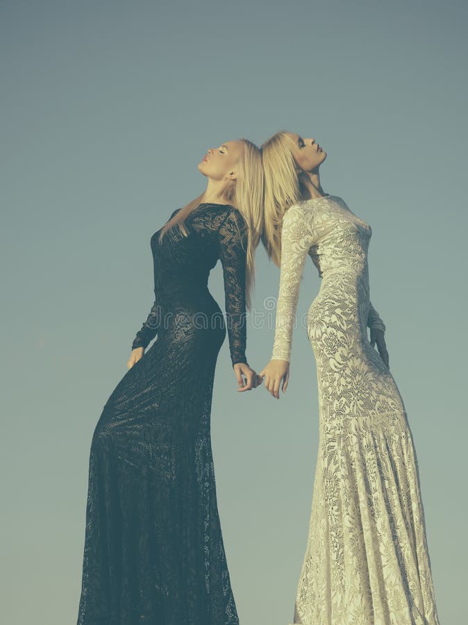 Twee meisjes met het lange blonde haar stellen op grijze hemel royalty-vrije stock fotografie Twee meisjes met het lange blonde haar stellen op grijze hemel royalty-vrije stock fotografie