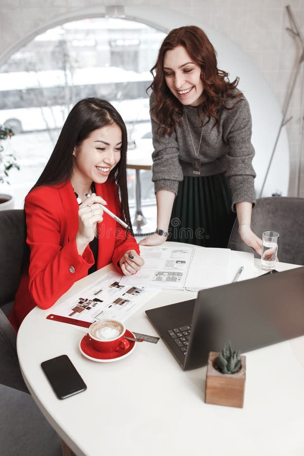 Twee meisjesontwerpers werken met laptop en documentatie bij het project in het modieuze bureau Projectverwezenlijking royalty-vrije stock fotografie Twee meisjesontwerpers werken met laptop en documentatie bij het project in het modieuze bureau Projectverwezenlijking royalty-vrije stock fotografie