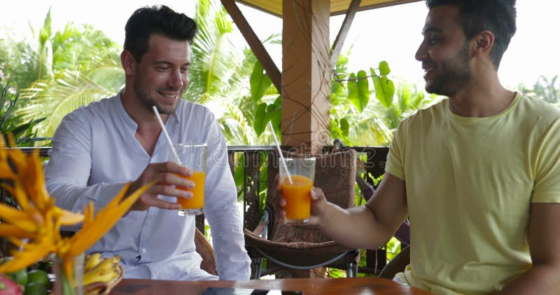 Twee mensen die op de zomerterras zitten die drinken jus d'orange, het vrolijke paar van het mengelingsras in ochtend op villa in