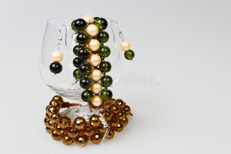 Twee met de hand gemaakte armbanden met oorringen in een glas cognac op ISO stock afbeeldingen Twee met de hand gemaakte armbanden met oorringen in een glas cognac op ISO stock afbeeldingen