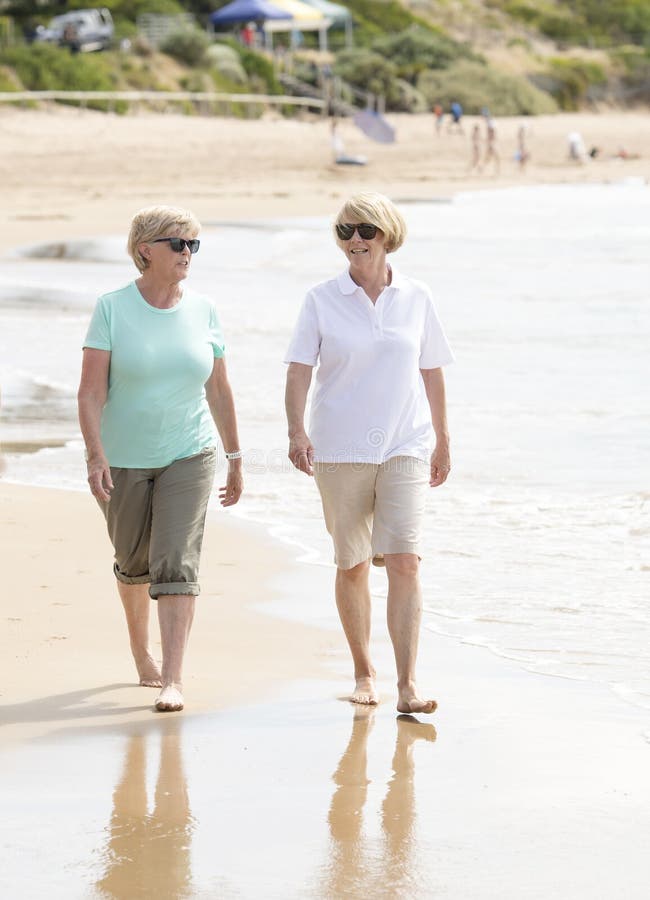 Twee mooie hogere rijpe teruggetrokken vrouwen op hun jaren '60 die pret hebben die samen van het gelukkige lopen op strand speel royalty-vrije stock foto Twee mooie hogere rijpe teruggetrokken vrouwen op hun jaren '60 die pret hebben die samen van het gelukkige lopen op strand speel royalty-vrije stock foto