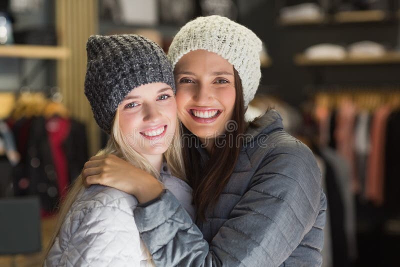 Twee mooie vrienden die met de winterkleren bij camera glimlachen stock foto Twee mooie vrienden die met de winterkleren bij camera glimlachen stock foto