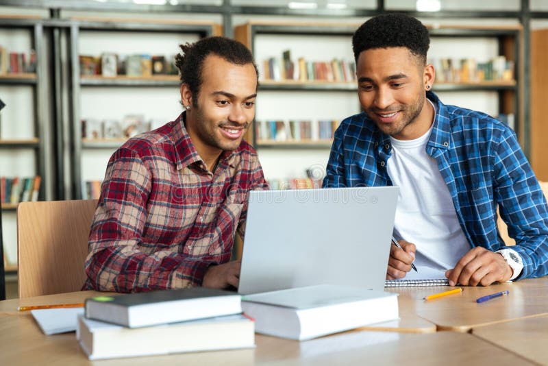 Twee multiculturele mannelijke studenten die met laptop bestuderen royalty-vrije stock foto Twee multiculturele mannelijke studenten die met laptop bestuderen royalty-vrije stock foto