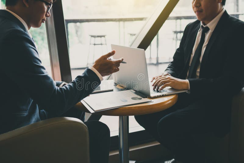 Two businessmen are talking about the results of operations in the company financial statements on the computer screen. Two businessmen are talking about the results of operations in the company financial statements on the computer screen.