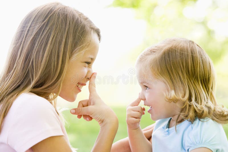 Twee in openlucht en zusters die spelen glimlachen royalty-vrije stock afbeelding Twee in openlucht en zusters die spelen glimlachen royalty-vrije stock afbeelding