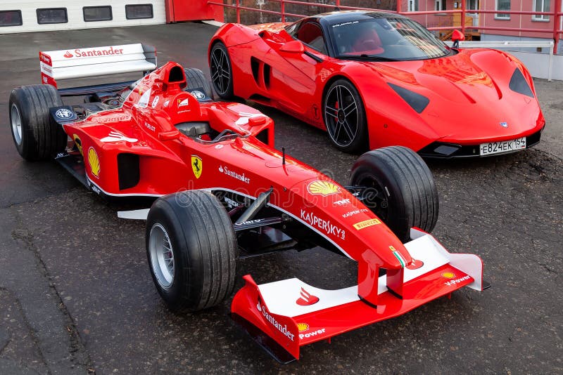 Twee rode Ferrari die sportwagens voor Formule 1 en Marrusia B1 racen op straat bij de garagedoos