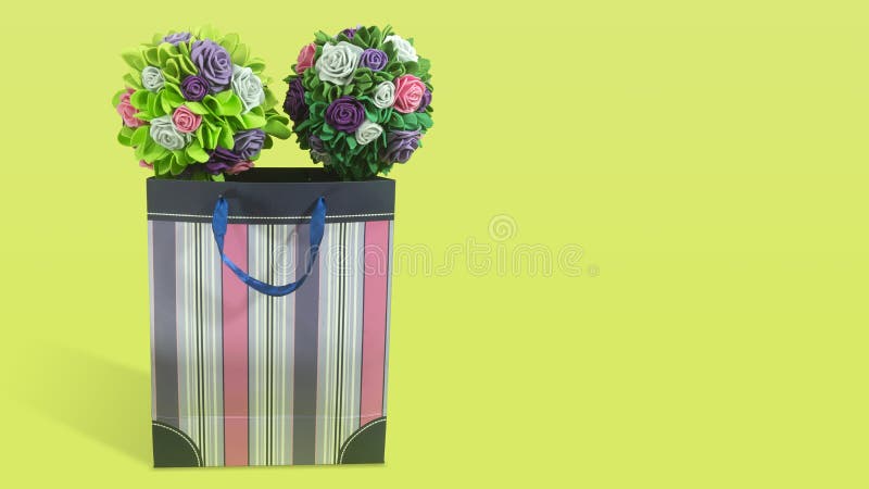 Twee rozenkappen met groene bladeren van schuim in een papieren cadeauzak met paarse strepen op groene achtergrond stock foto's Twee rozenkappen met groene bladeren van schuim in een papieren cadeauzak met paarse strepen op groene achtergrond stock foto's