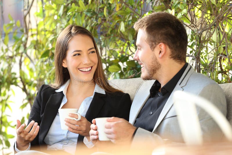 Twee stafmedewerkers die in een koffiepauze spreken stock afbeeldingen Twee stafmedewerkers die in een koffiepauze spreken stock afbeeldingen