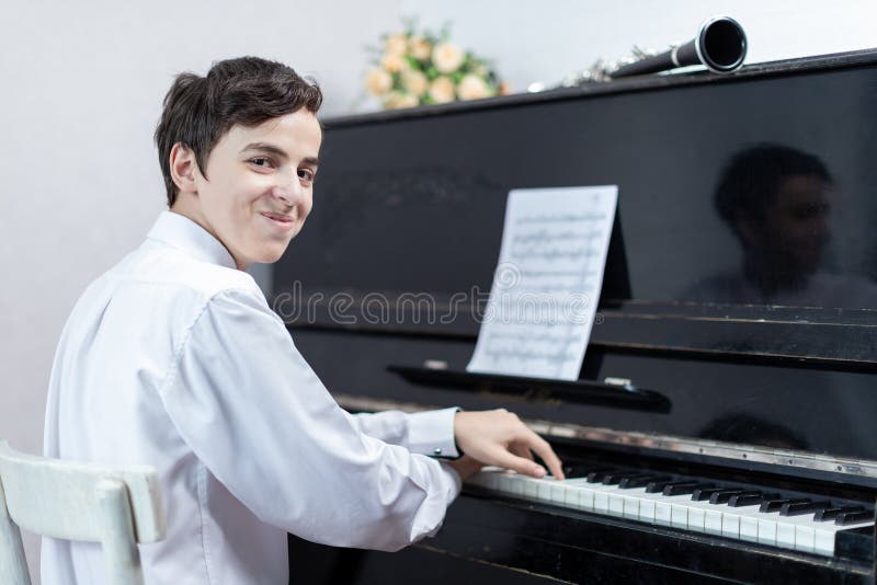 Two teenage boys play piano in class or at home . two students learn to play the piano. Two teenage boys play piano in class or at home . two students learn to play the piano