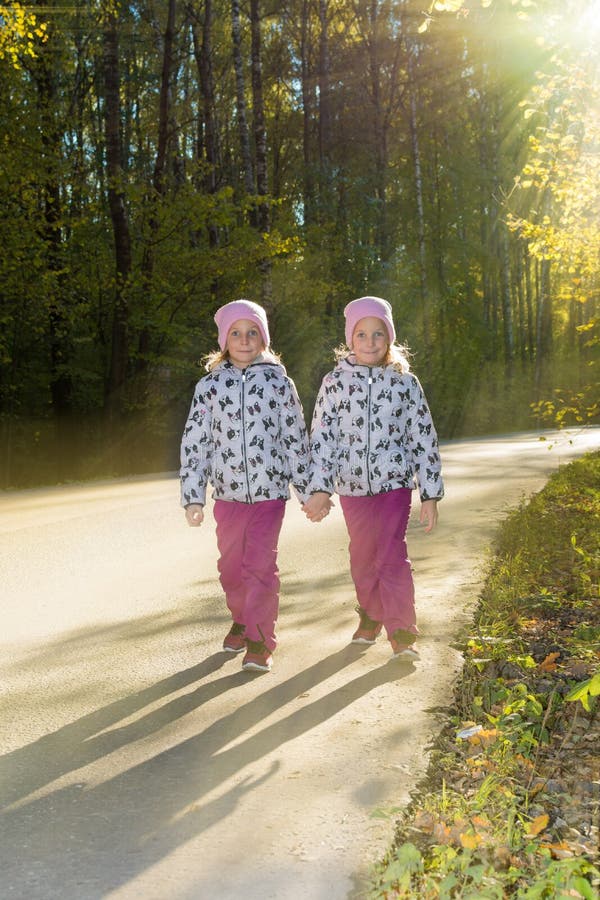 Twee tweelingzusters gaan hand in hand door het de herfstpark royalty-vrije stock foto's Twee tweelingzusters gaan hand in hand door het de herfstpark royalty-vrije stock foto's