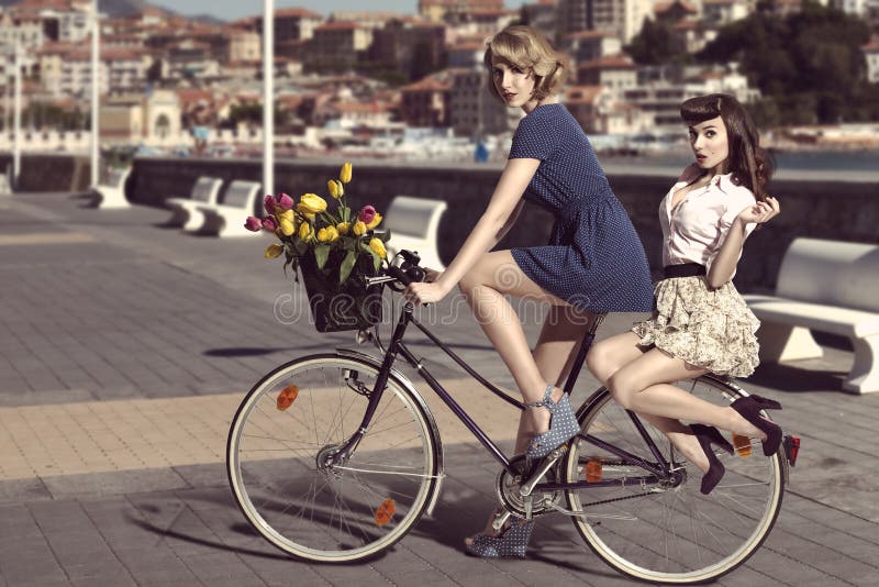 Twee uitstekende vrouwen op fiets dichtbij het overzees royalty-vrije stock foto Twee uitstekende vrouwen op fiets dichtbij het overzees royalty-vrije stock foto
