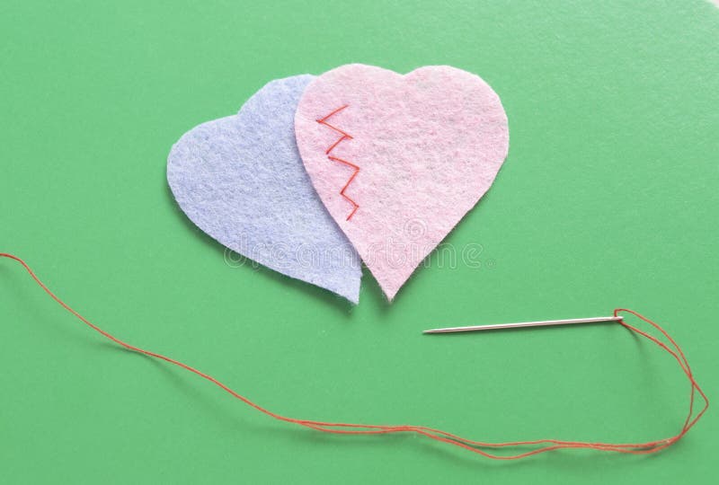 two fabric hearts sewn together on a green background. two fabric hearts sewn together on a green background