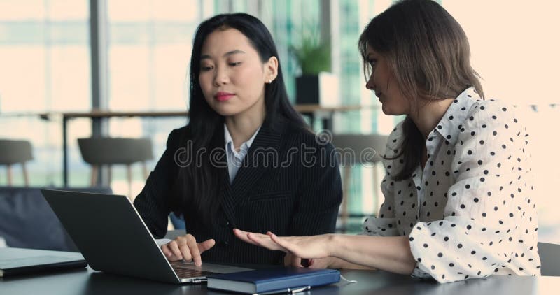 Twee verschillende jonge zakelijke collega's die op laptop praten