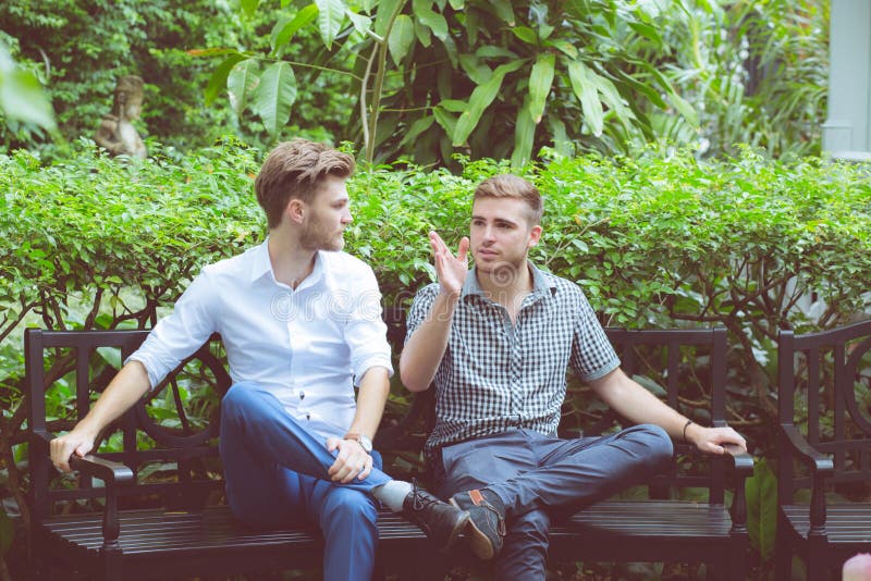 Twee vriendenmensen die zitting in een tuin spreken royalty-vrije stock afbeelding Twee vriendenmensen die zitting in een tuin spreken royalty-vrije stock afbeelding