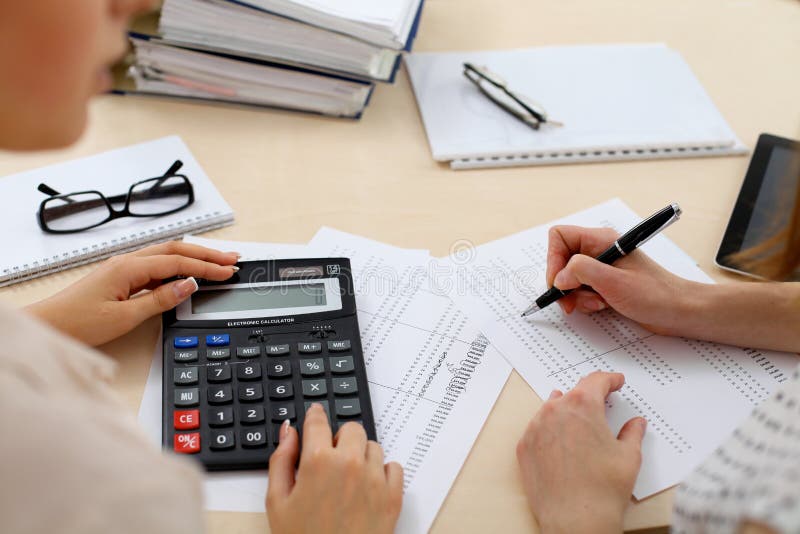 Twee vrouwelijke accountants die op calculatorinkomen tellen voor de close-up van de voltooiingshanden van de belastingsvorm De d royalty-vrije stock afbeelding Twee vrouwelijke accountants die op calculatorinkomen tellen voor de close-up van de voltooiingshanden van de belastingsvorm De d royalty-vrije stock afbeelding