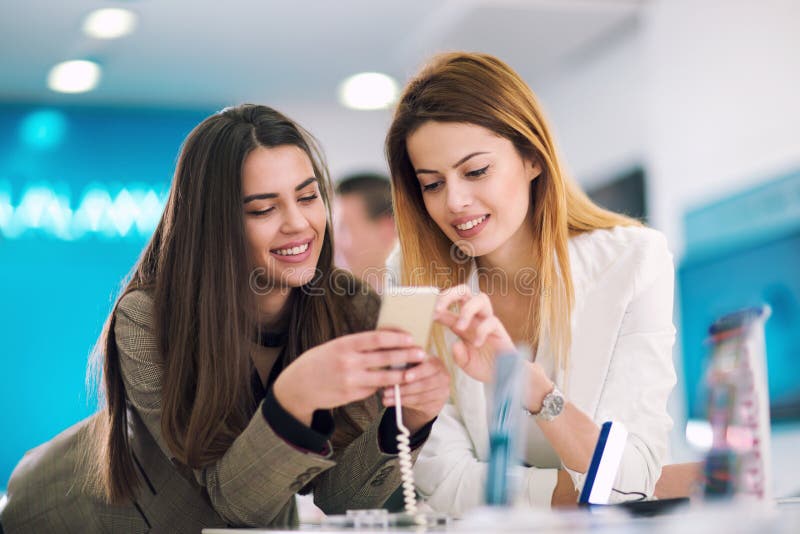 Twee vrouwen die een mobiele telefoon in opslag houden royalty-vrije stock fotografie Twee vrouwen die een mobiele telefoon in opslag houden royalty-vrije stock fotografie