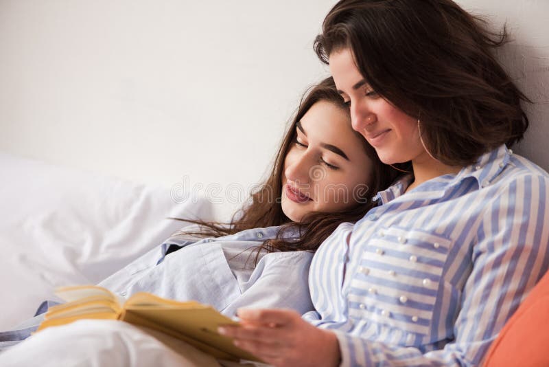 Twee vrouwen lagen in bed met boek stock foto's Twee vrouwen lagen in bed met boek stock foto's