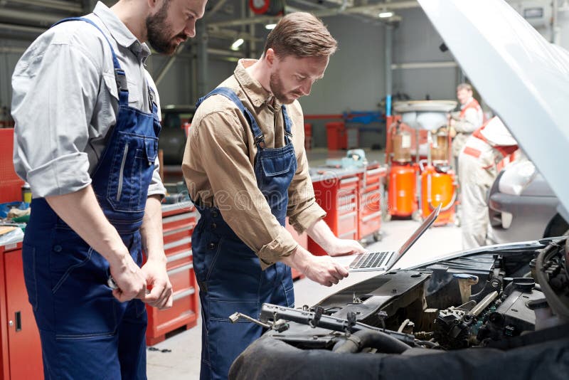 Twee Werktuigkundigen het Inspecteren Auto royalty-vrije stock afbeeldingen Twee Werktuigkundigen het Inspecteren Auto royalty-vrije stock afbeeldingen