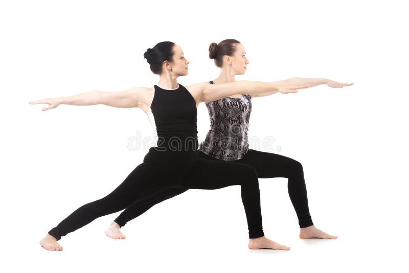 Twee Yogimeisjes die zich in yogastrijder II bevinden stellen stock foto's Twee Yogimeisjes die zich in yogastrijder II bevinden stellen stock foto's