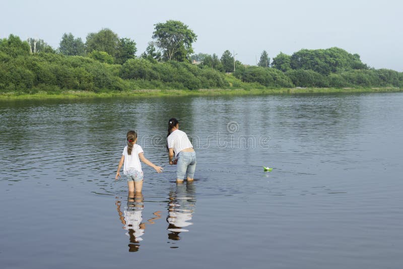 Twee zusters die met document boten door een rivier spelen stock foto's Twee zusters die met document boten door een rivier spelen stock foto's