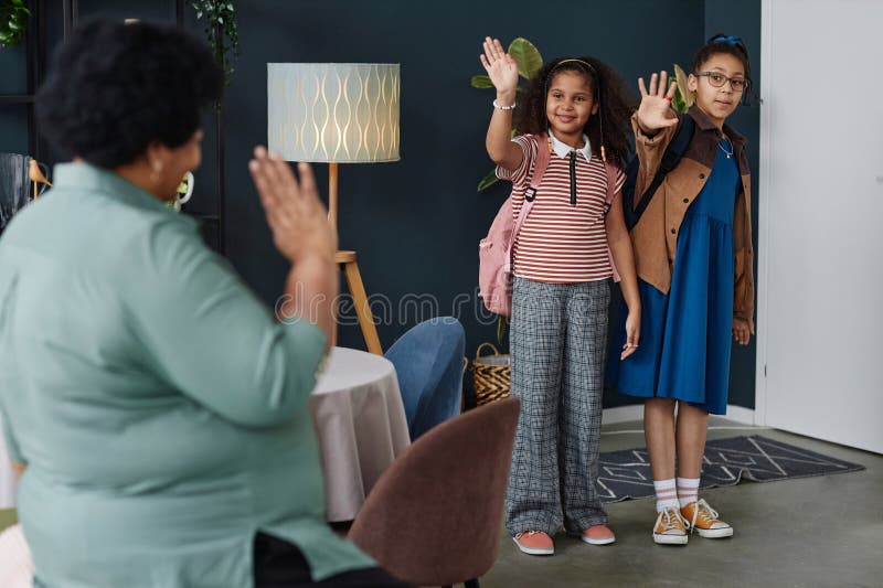 Full length portrait of two young African American girls waving to grandma leaving for school in morning copy space. Full length portrait of two young African American girls waving to grandma leaving for school in morning copy space