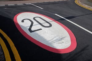 Twenty Mile An Hour Speed Limit Sign Painted On Tarmac Road Surface 