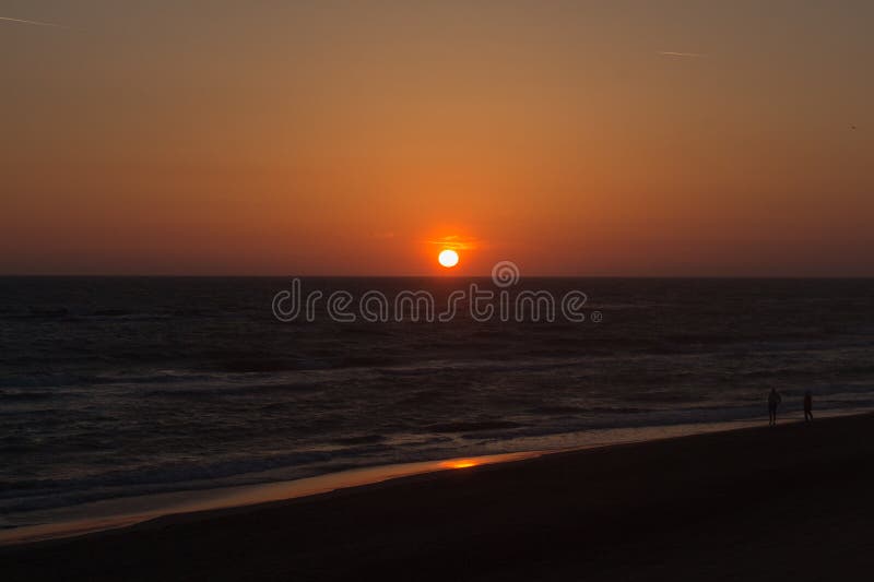Twilight before the sun sets over Tyrrhenian sea. Two people at sandy beach watching sunset royalty free stock photos Twilight before the sun sets over Tyrrhenian sea. Two people at sandy beach watching sunset royalty free stock photos