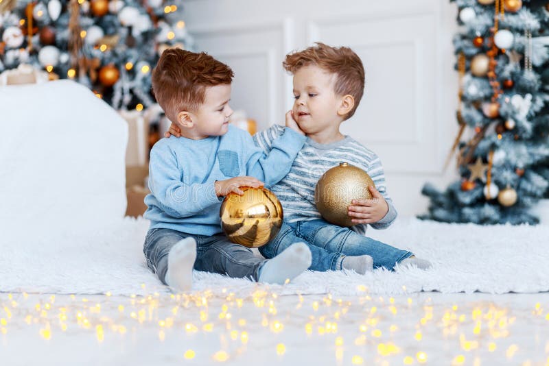 Twin brothers in front of the christmas tree with candles and gifts. love, happiness and big family concept royalty free stock photo Twin brothers in front of the christmas tree with candles and gifts. love, happiness and big family concept royalty free stock photo