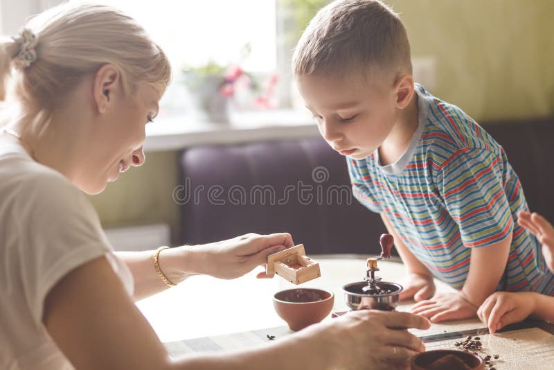 Twin brothers helping her mother to grind coffee stock photography Twin brothers helping her mother to grind coffee stock photography