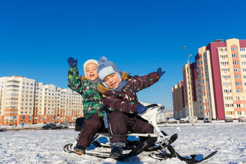 Twin brothers posing on snow scooter royalty free stock images Twin brothers posing on snow scooter royalty free stock images
