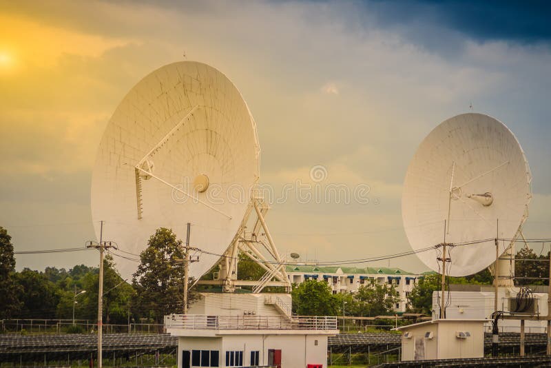 Twin large scale white satellite dish in solar farm under dramatic blue and cloudy sky background. royalty free stock photography Twin large scale white satellite dish in solar farm under dramatic blue and cloudy sky background. royalty free stock photography
