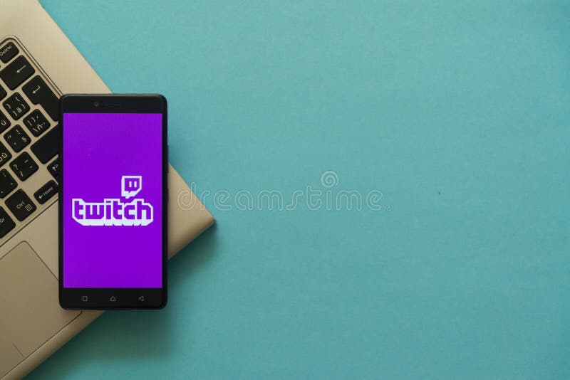 Twitch logo on smartphone placed on laptop keyboard.