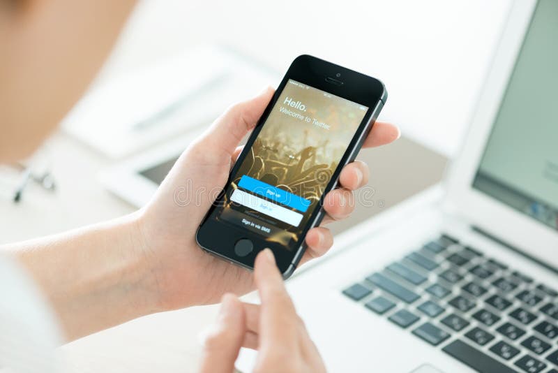 KIEV, UKRAINE - JUNE 27, 2014: Person holding a brand new Apple iPhone 5S with Twitter app login page on the screen. Twitter is a social media online service for microblogging and networking, founded in March 21, 2006. KIEV, UKRAINE - JUNE 27, 2014: Person holding a brand new Apple iPhone 5S with Twitter app login page on the screen. Twitter is a social media online service for microblogging and networking, founded in March 21, 2006.