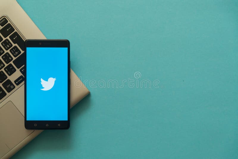 Twitter logo on smartphone placed on laptop keyboard.