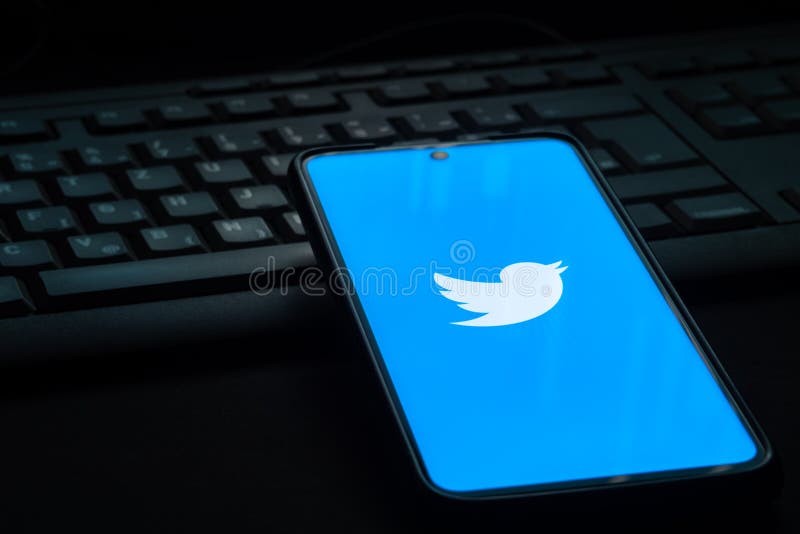 Twitter logo on smartphone screen laying on computer keyboard