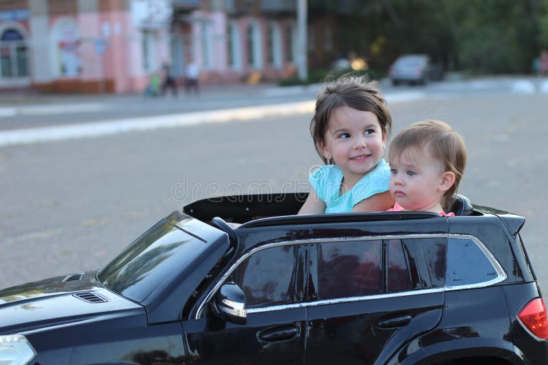 Dve úžasný dievčatá jazda v jeden veľký hračka auto na mesto ulice asfalt.