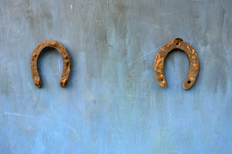 Two ancient rusty horseshoe on blue wall royalty free stock image