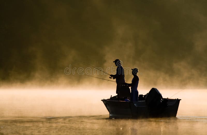 Due pescatori di pesca in una nebbiosa illuminata dal sole del lago.