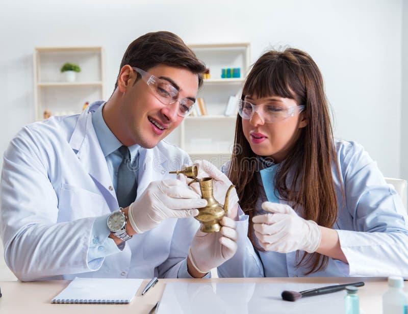 Two archeologists looking at ancient gold lamp