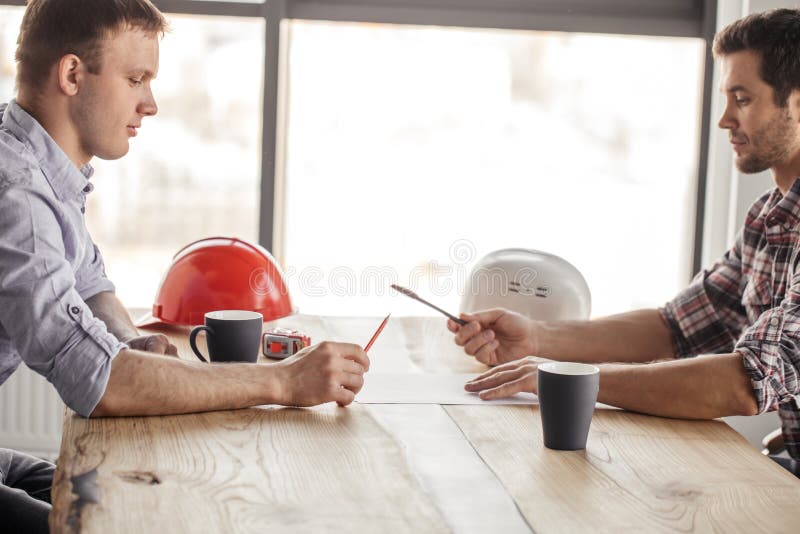 Two architects are having fun with a pen and a pencil while drinking royalty free stock image Two architects are having fun with a pen and a pencil while drinking royalty free stock image
