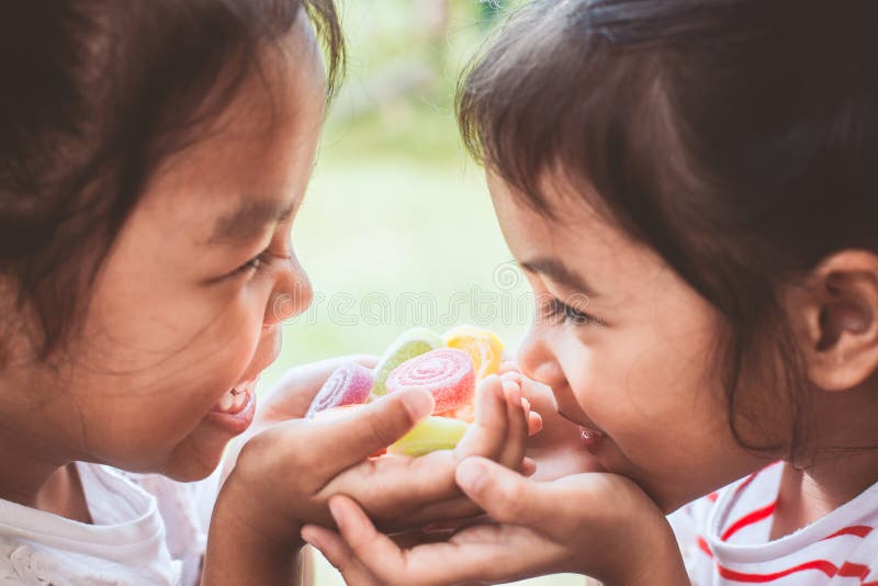 Two asian child girls holding sweet candies in thier hands