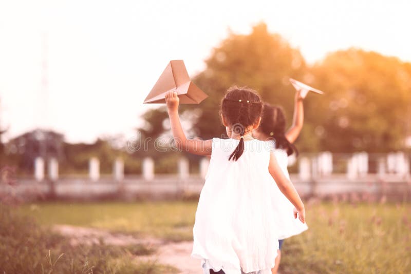 Two asian child girls running and playing toy paper airplane