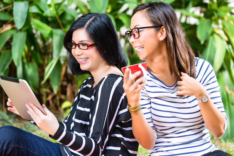 https://thumbs.dreamstime.com/b/two-asian-girlfriends-tablet-computer-indonesian-friends-looking-tropical-environment-36009053.jpg