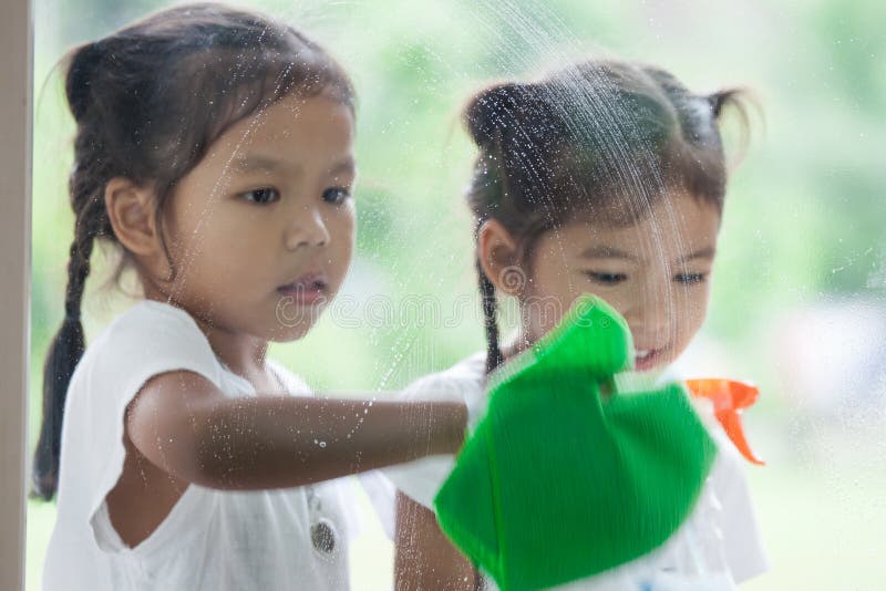 Two asian little child girls help parent to clean window royalty free stock photography Two asian little child girls help parent to clean window royalty free stock photography