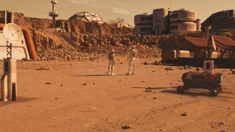 Two astronauts walk on Mars surface near scientific base stock photo