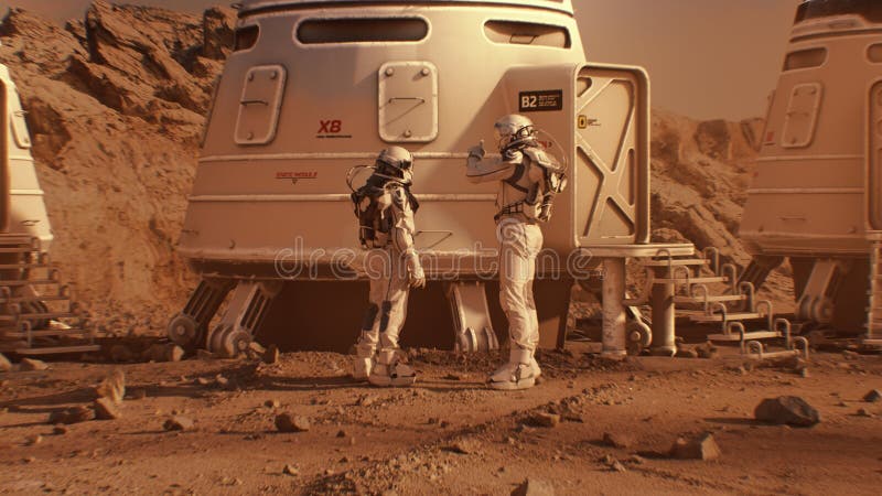 Two astronauts in spacesuits walk toward base on Mars stock image