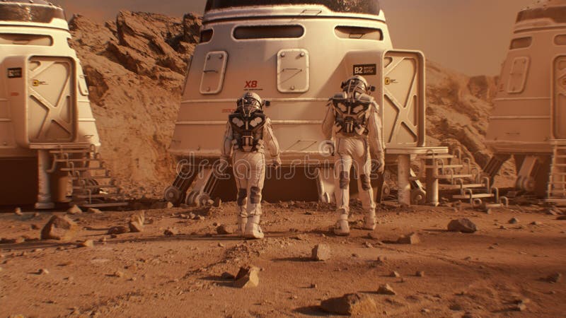 Two astronauts in spacesuits walk toward base on Mars royalty free stock images