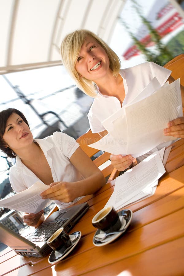 Two attractive girls with laptop drinking coffee