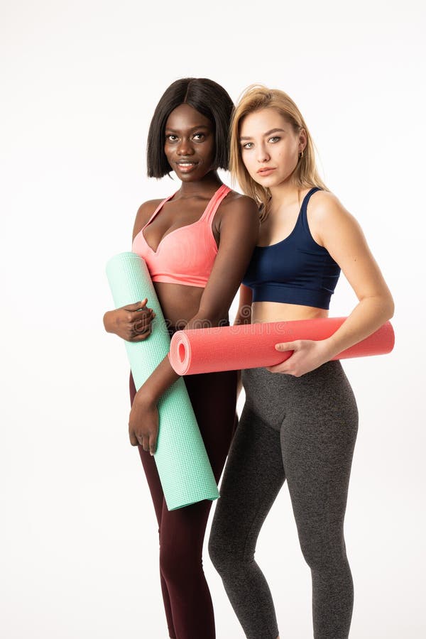 Two attractive international girls. Practicing yoga every day. Girls slim fit athlete holding fitness mat. Fitness and