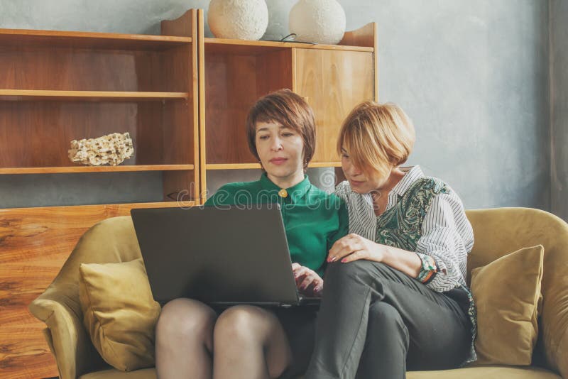 Two attractive mid adult women with laptop at home royalty free stock photo Two attractive mid adult women with laptop at home royalty free stock photo